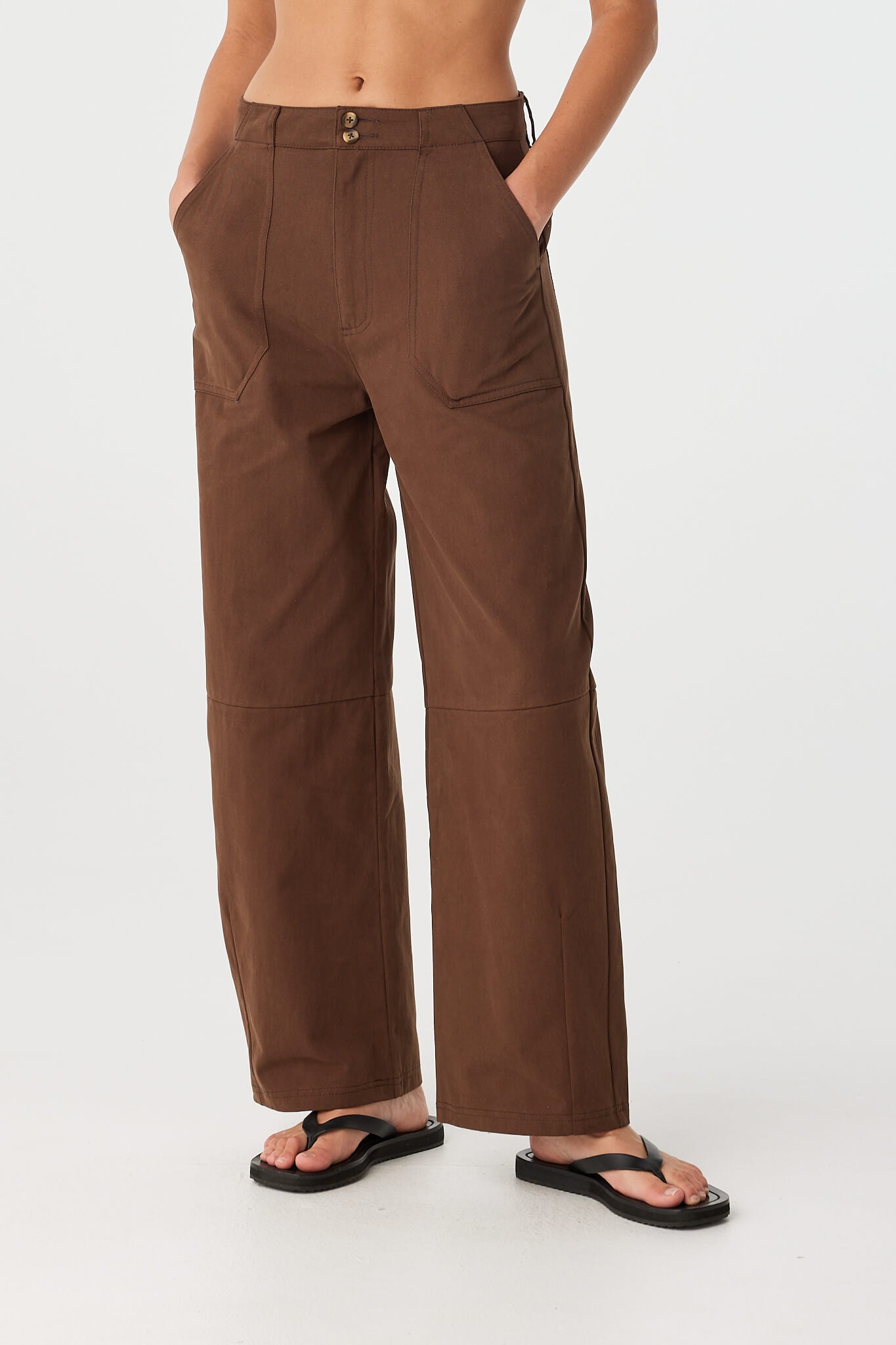 Relaxed stance with hands in pockets, highlighting structured silhouette of cotton barrel-leg pants.