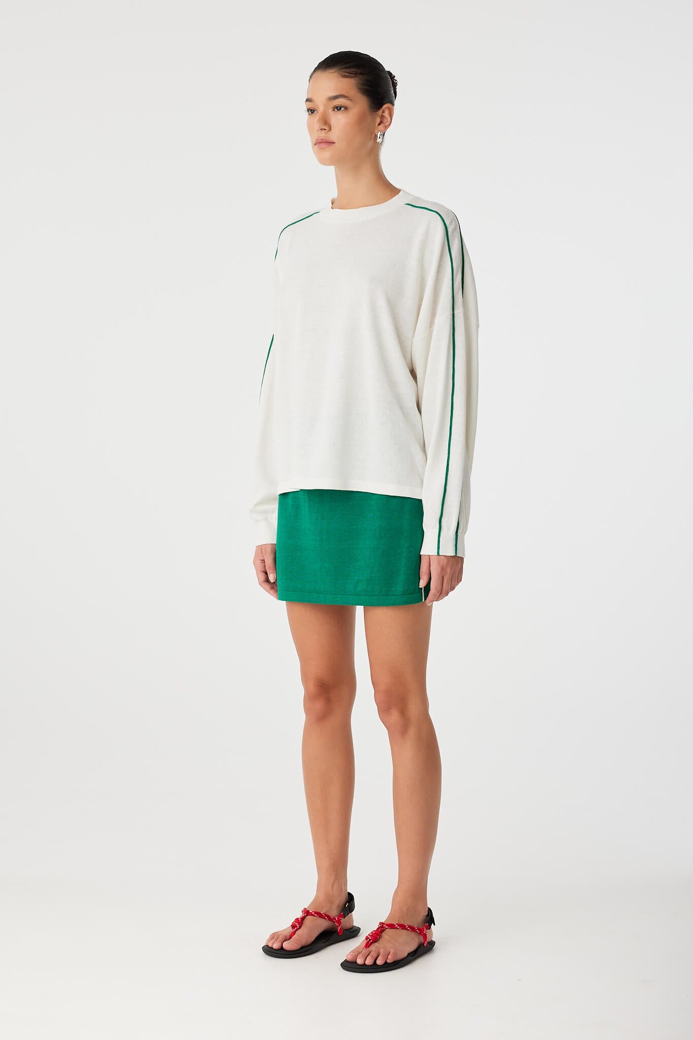 Side profile of oversized long sleeve knit with stripe sleeve detail and airy drape.