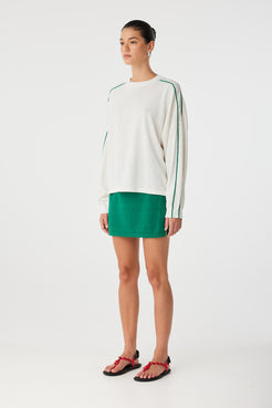 Side profile of oversized long sleeve knit with stripe sleeve detail and airy drape.