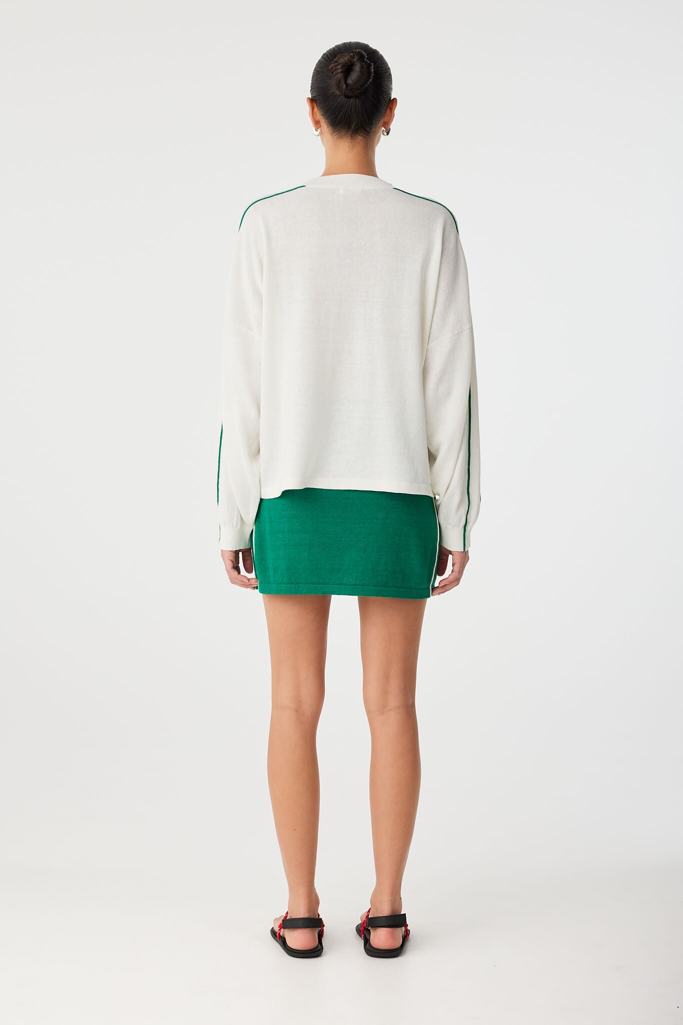 Back view of knit long sleeve tee in cream, styled with matching green mini skirt.
