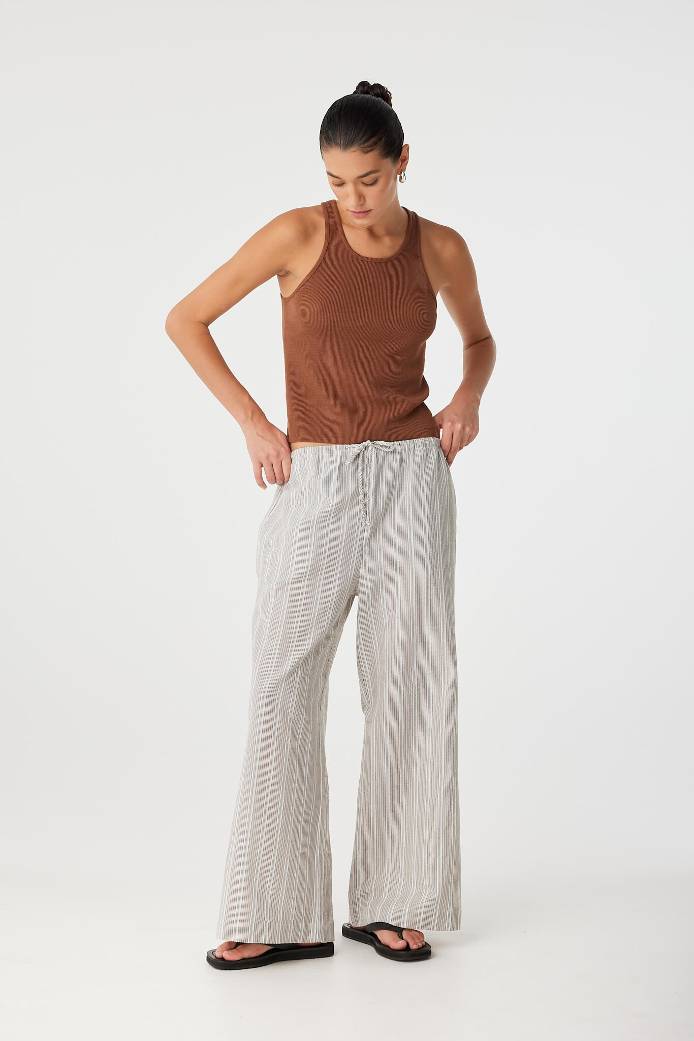 Model with hands on hips wearing clay stripe pant styled for elevated casual dressing.