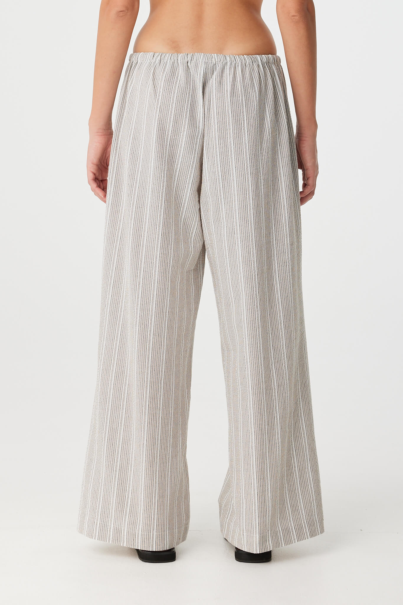 Back view of model wearing striped pant in soft cotton, showing relaxed drape and waistband.