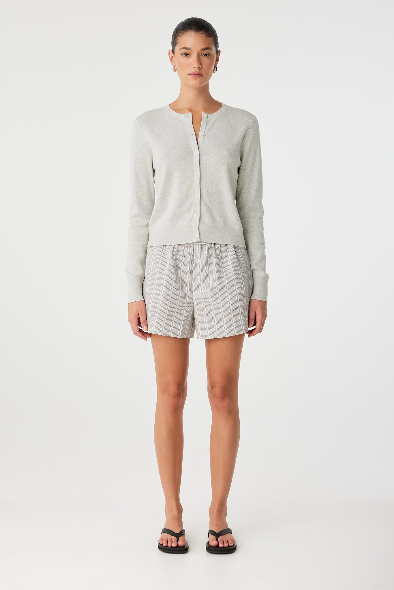 Model wears Flynn Cardigan over shorts, highlighting slim fit and lightweight knit.