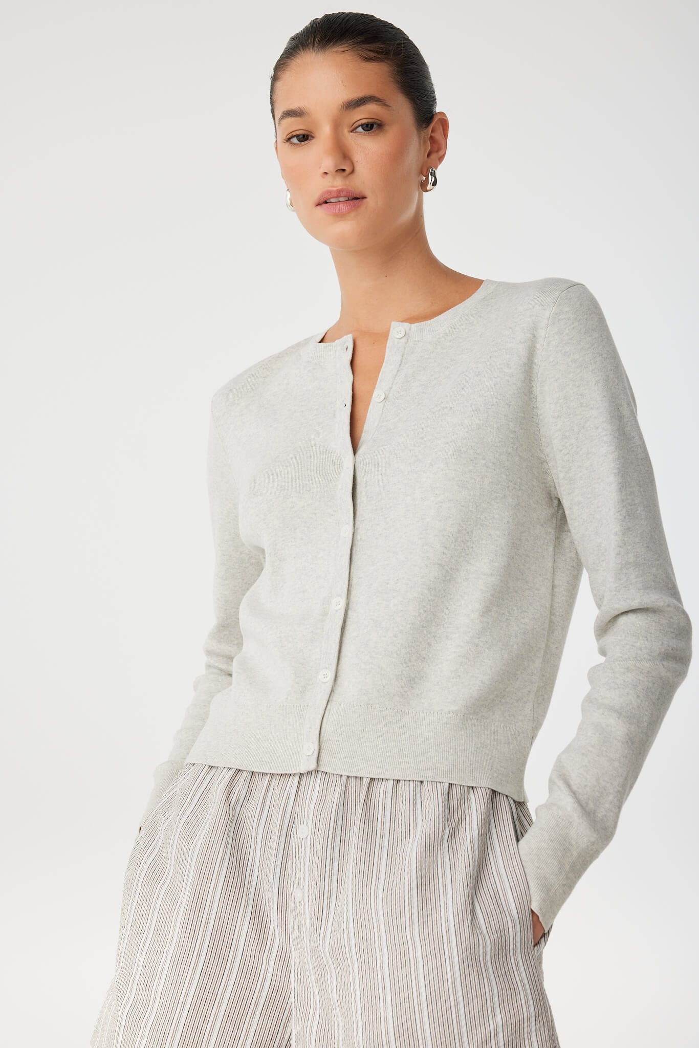 Side view of model in grey cardigan and striped shorts, showing soft knit layering.