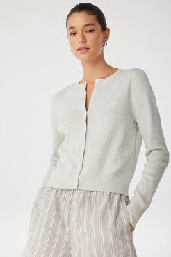 Side view of model in grey cardigan and striped shorts, showing soft knit layering.