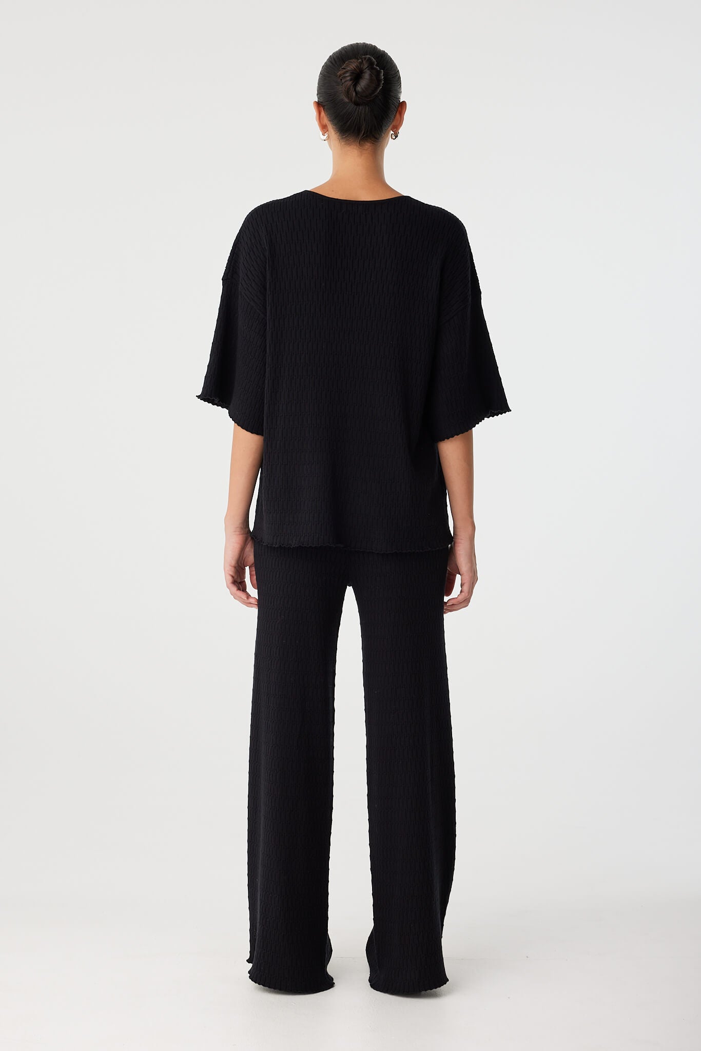 Back view of model wearing full black outfit with relaxed straight-leg pant.