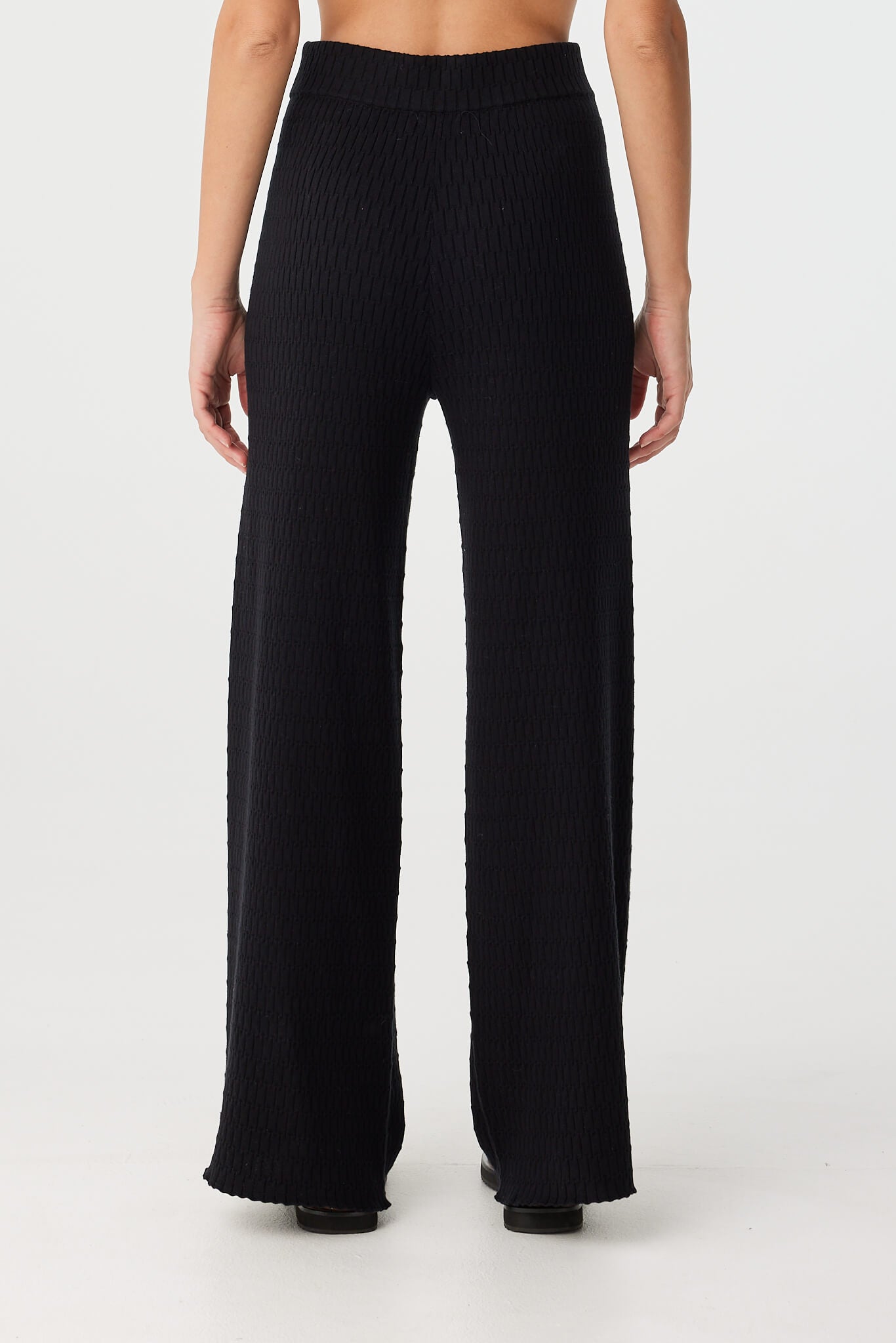 Back view of black straight-leg knit pant with subtle drape and relaxed structure.