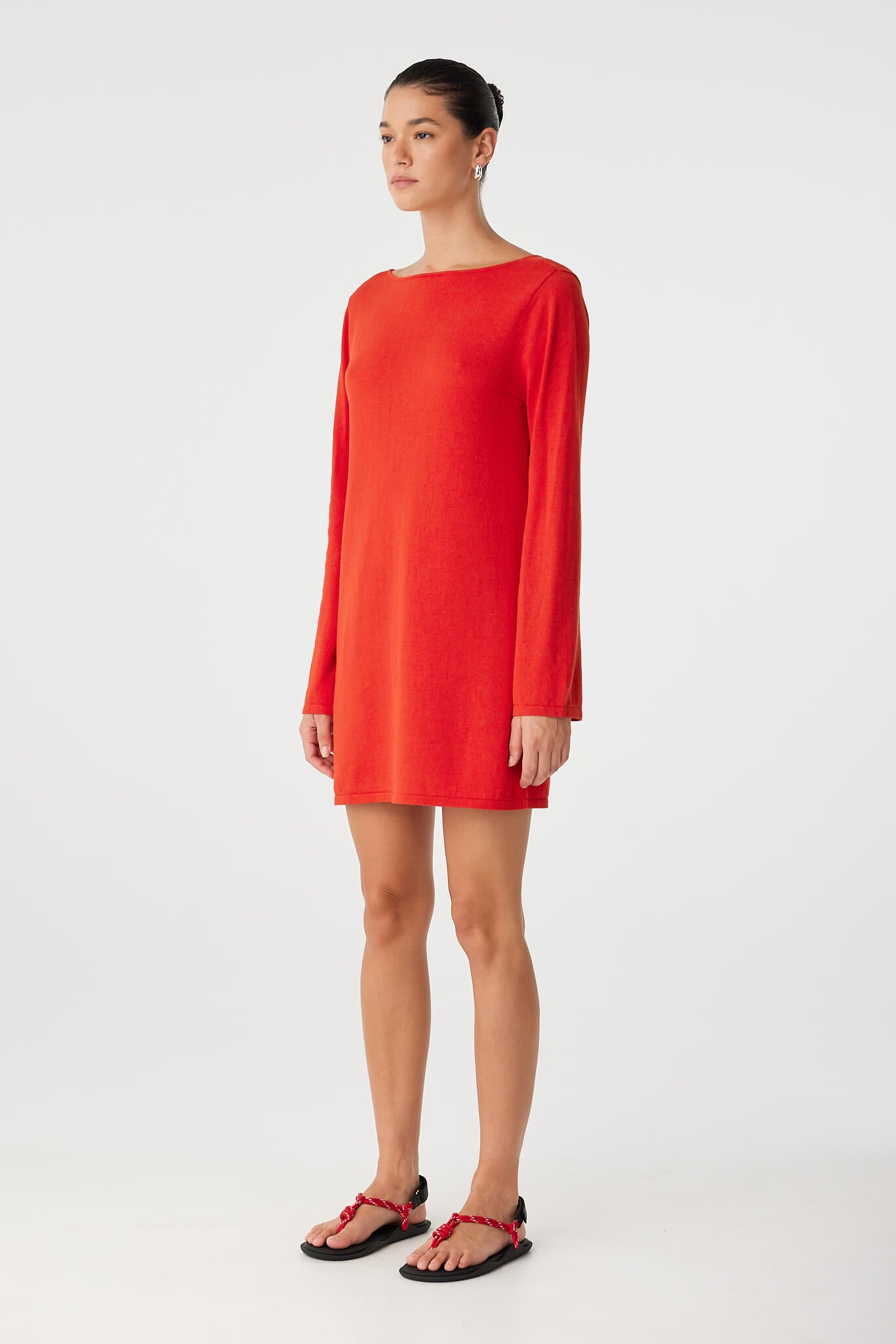 Side profile of reversible shift dress in warm red with clean crew neckline and soft drape, ideal for layering.