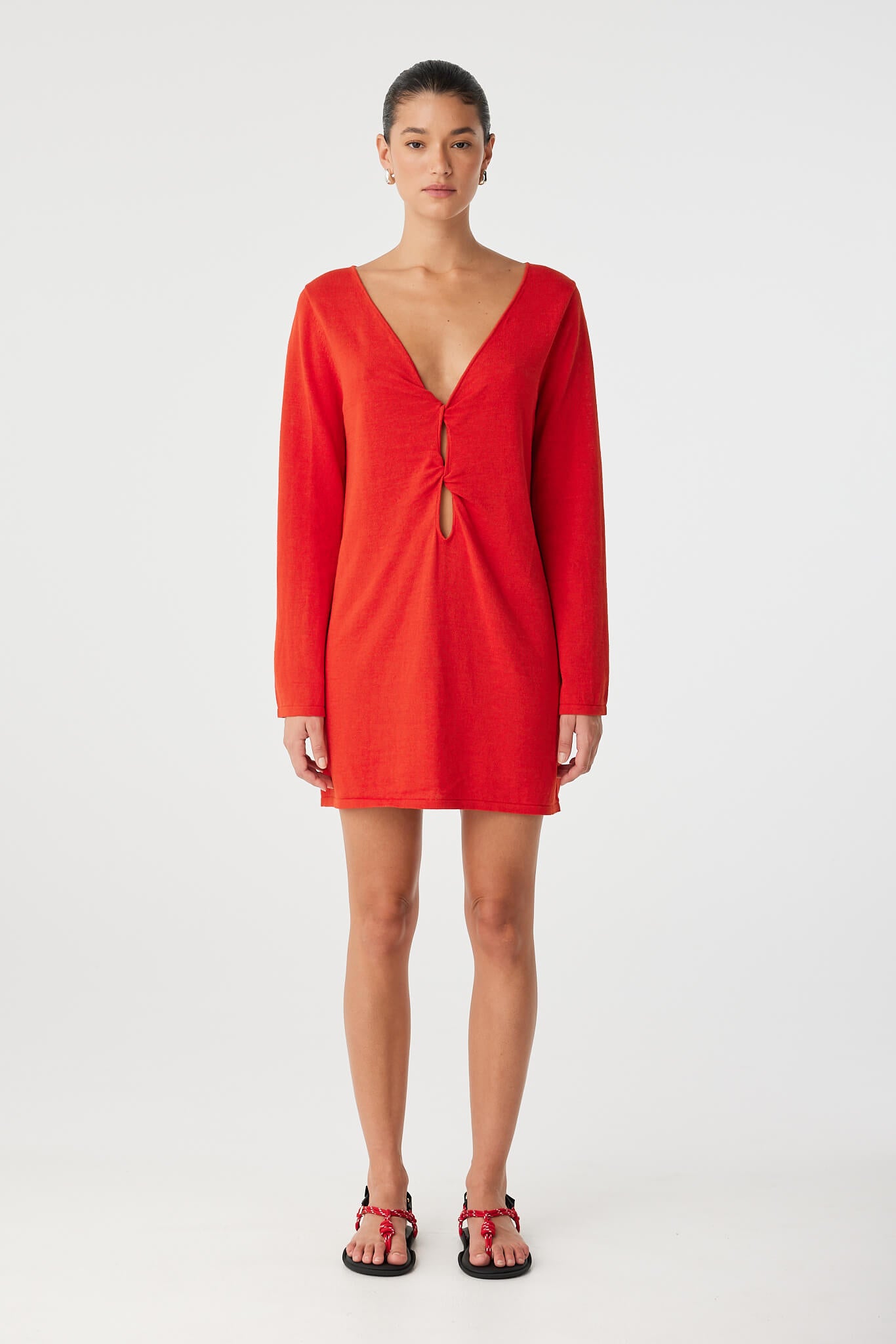 Model wears cherry red shift dress with long sleeves and twist cut-out at front, crafted in breathable linen–cotton blend.
