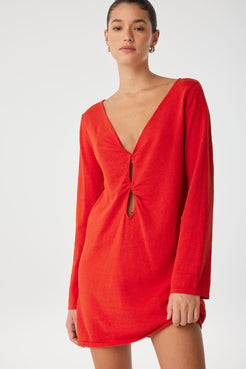 Twist-front reversible shift dress in bright red, styled with sandals—crafted for movement and transitional ease.