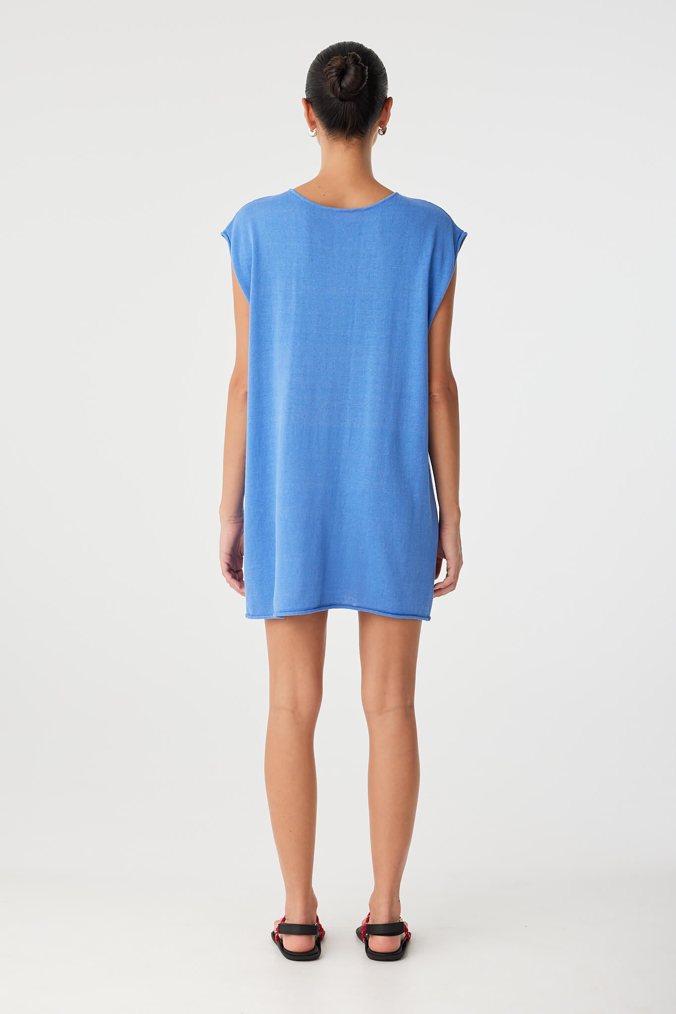 Back view of the Pala Dress worn with high neckline and smooth back, showing clean shift silhouette in breathable pacific blue linen–cotton blend.