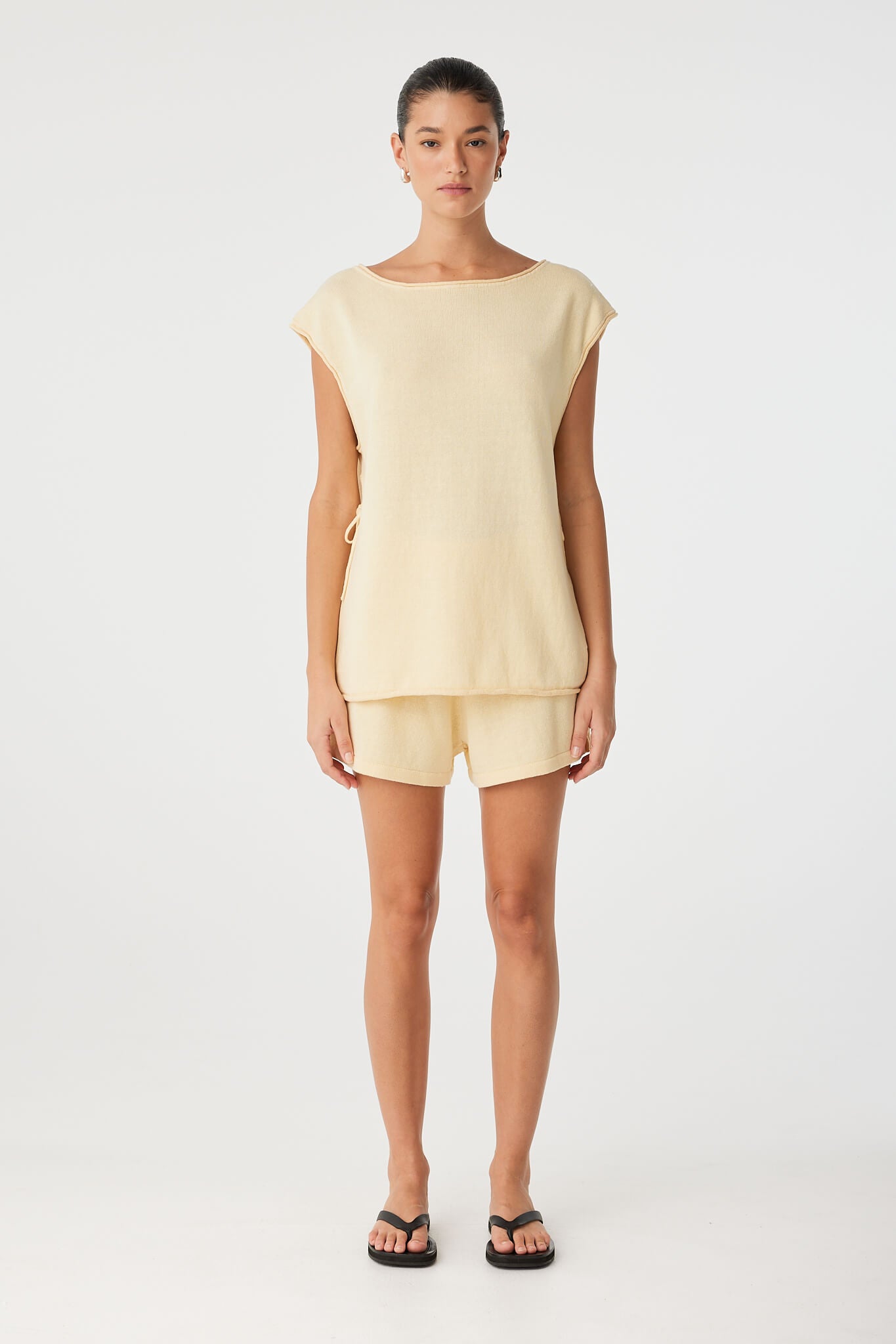 Oversized sleeveless top with split hem and raw edge neckline in butter yellow.