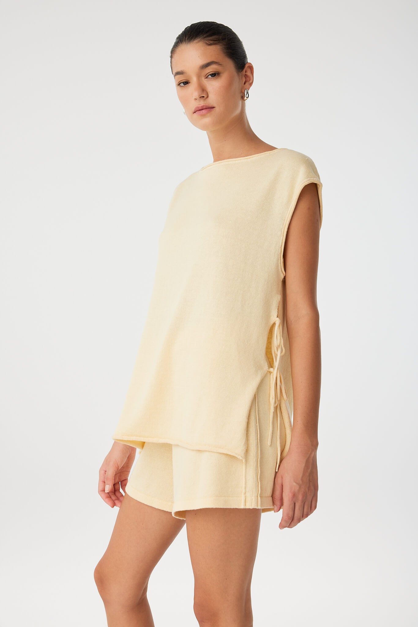 Side view of linen shorts styled with matching top, showing side pleat and soft drape.
