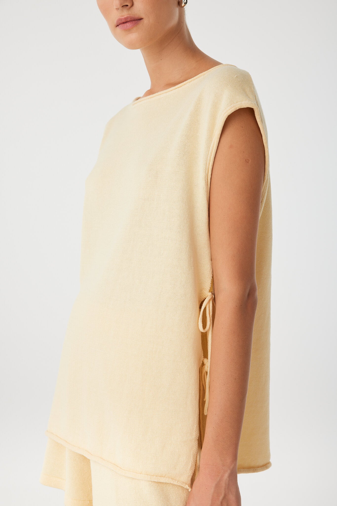 Detail of side tie and rolled armhole on softly textured sleeveless top.