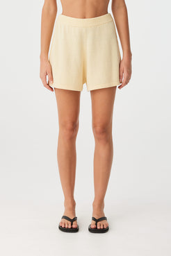 Front view of relaxed butter shorts in linen–cotton blend with elastic waistband and pleated sides.
