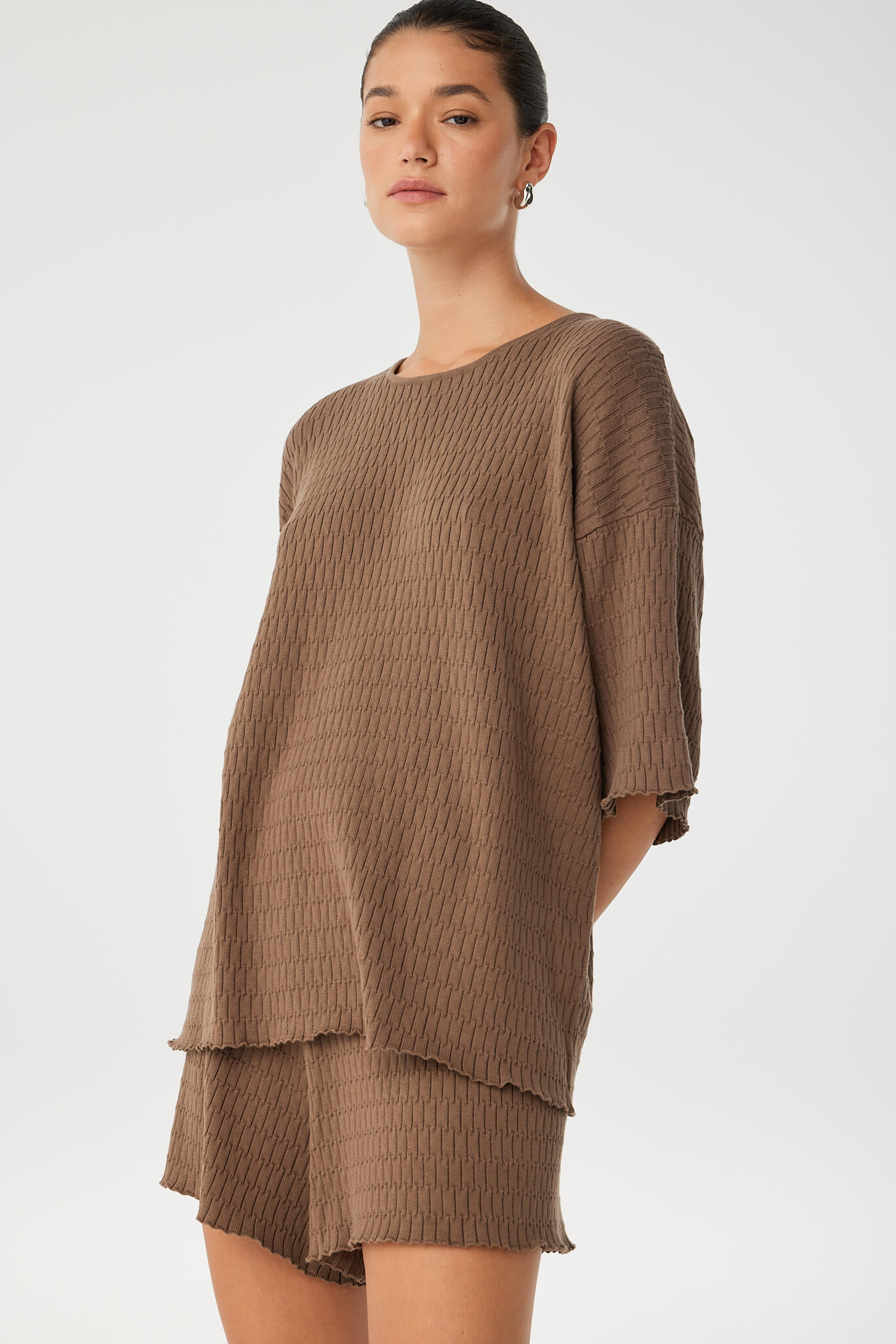 Close view of waffle-textured knit fabric and wide sleeve silhouette, crafted from breathable organic cotton.