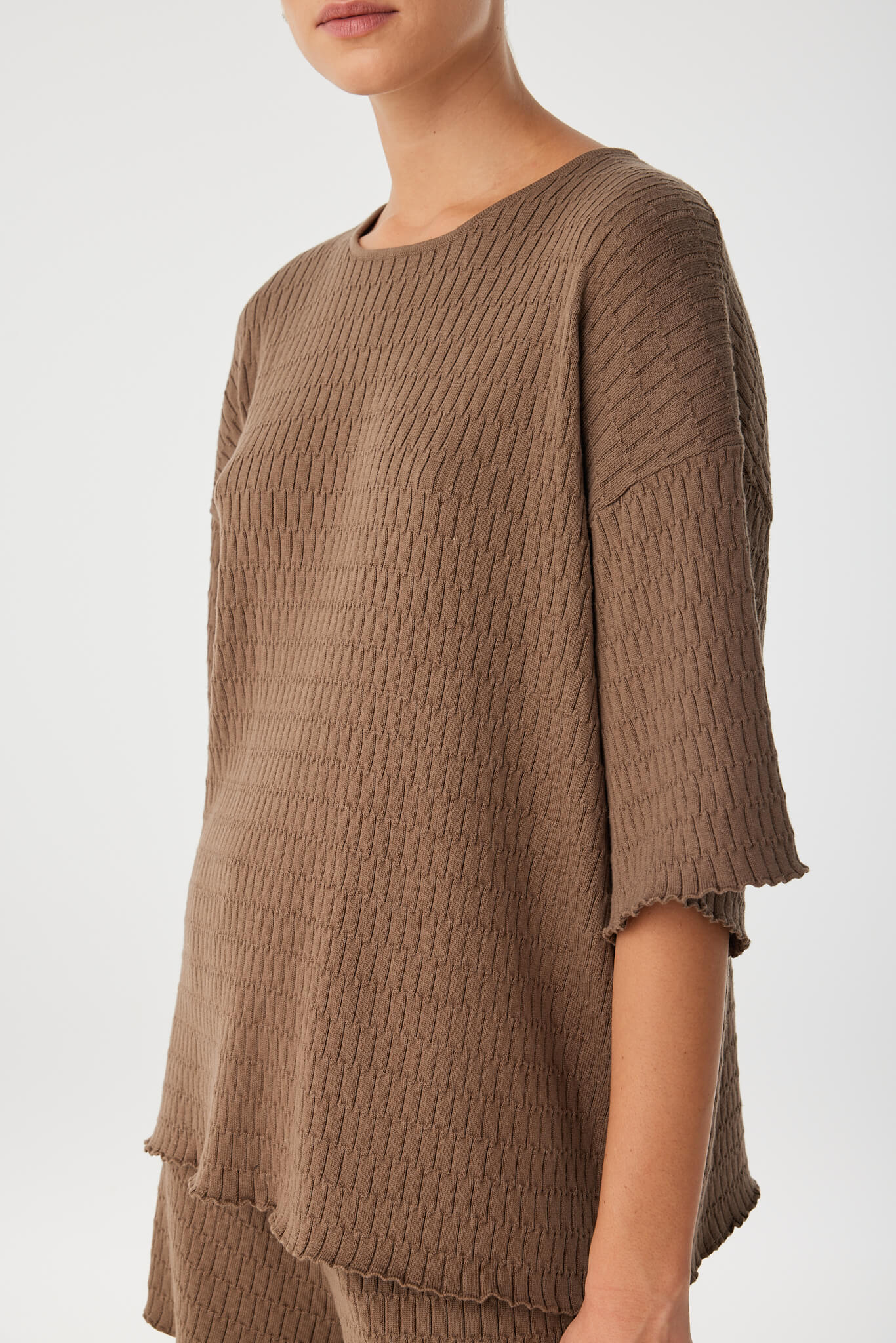 Editorial close-up of crew neckline and textured knit pattern, showing high-quality finish and natural drape.