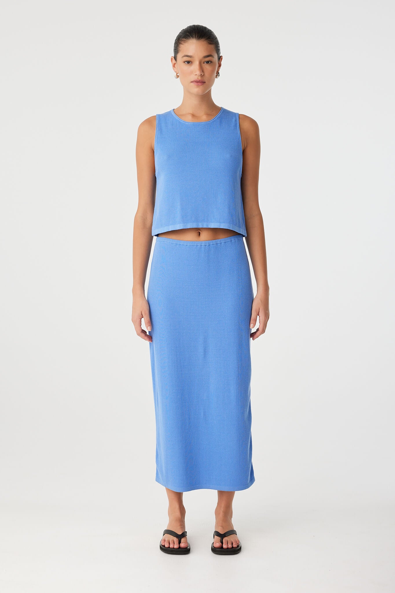 Model wears longline ribbed knit skirt in pacific blue, styled with matching tank—crafted in a lightweight cotton–hemp blend for breathable layering.