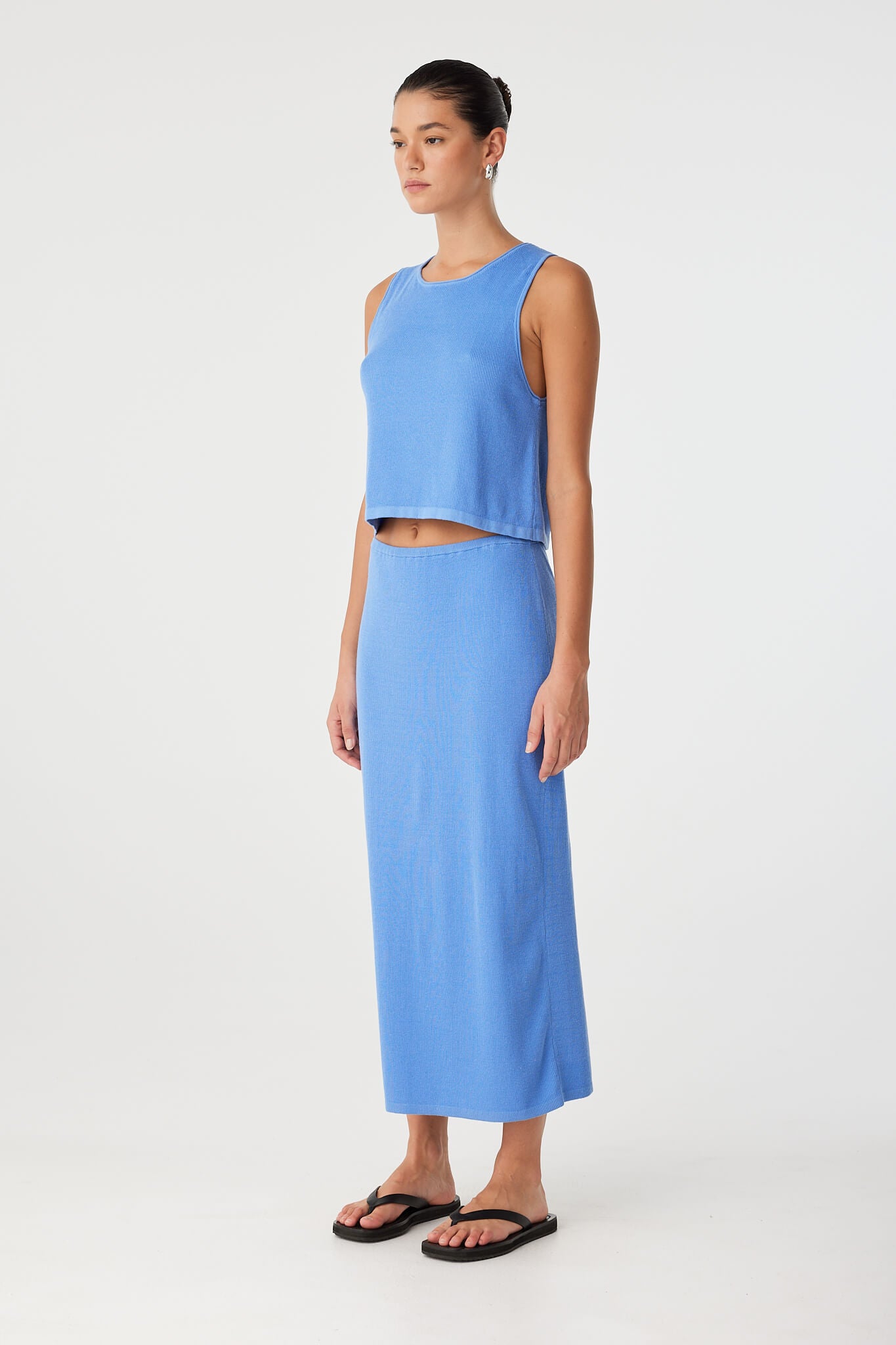 Model in pacific blue ribbed skirt worn high on the waist, highlighting soft knit movement and minimal hem.