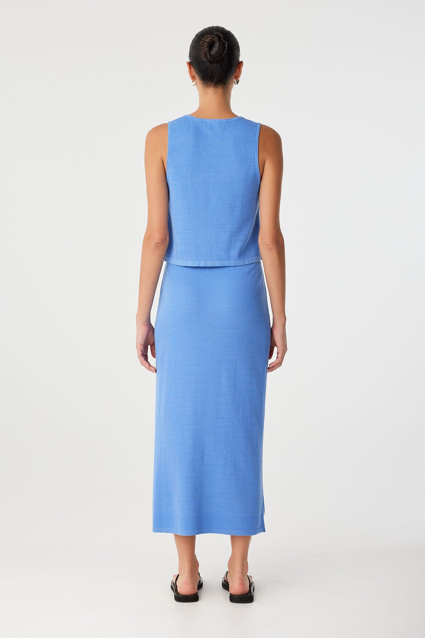 Back view of blue tank top showing high neckline, ribbed texture and clean, flared hemline.