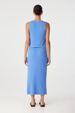 Back view of blue tank top showing high neckline, ribbed texture and clean, flared hemline.