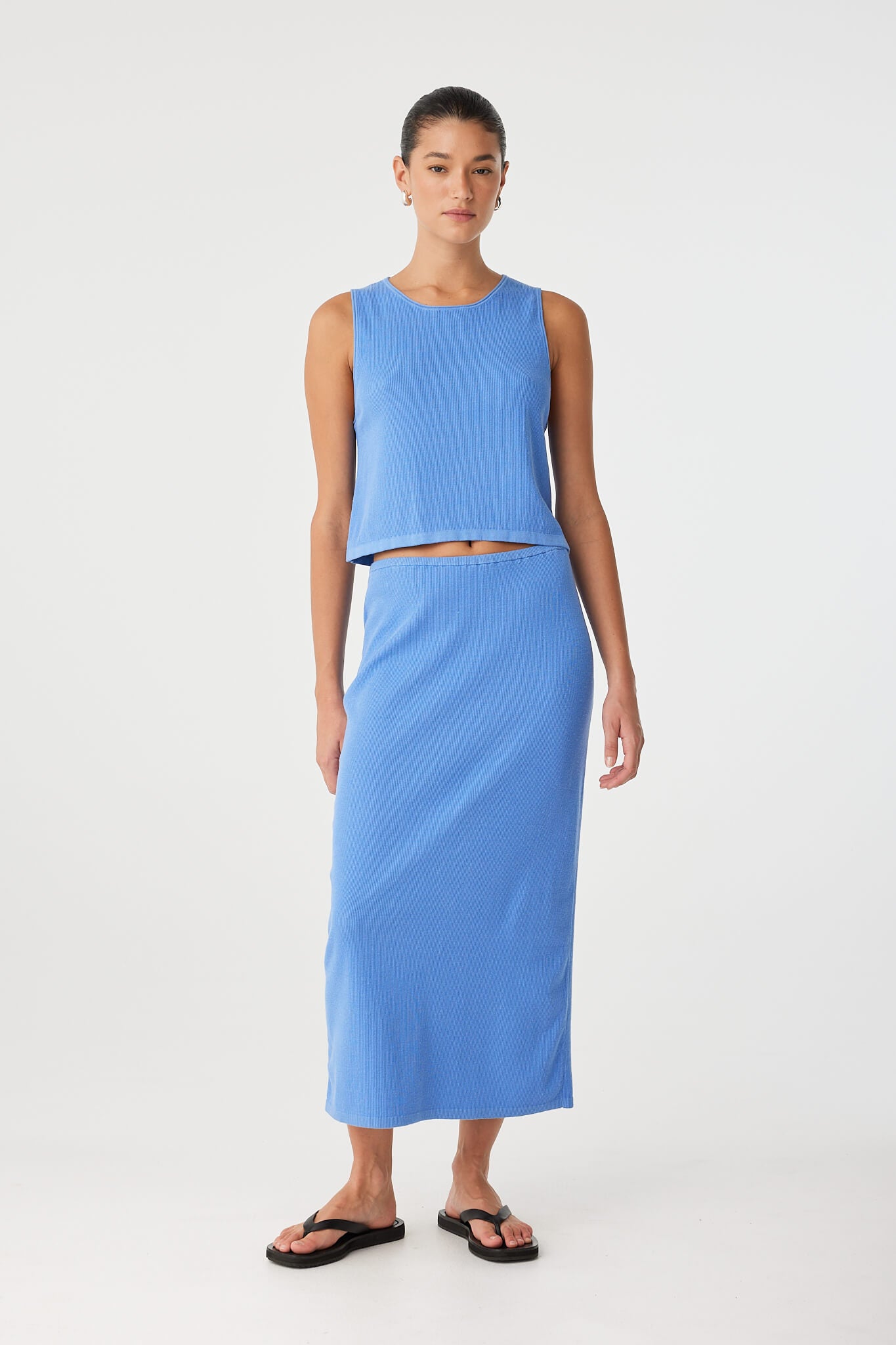 Model in blue sleeveless tank with subtle ribbing and natural drape—part of a breathable seasonal set.