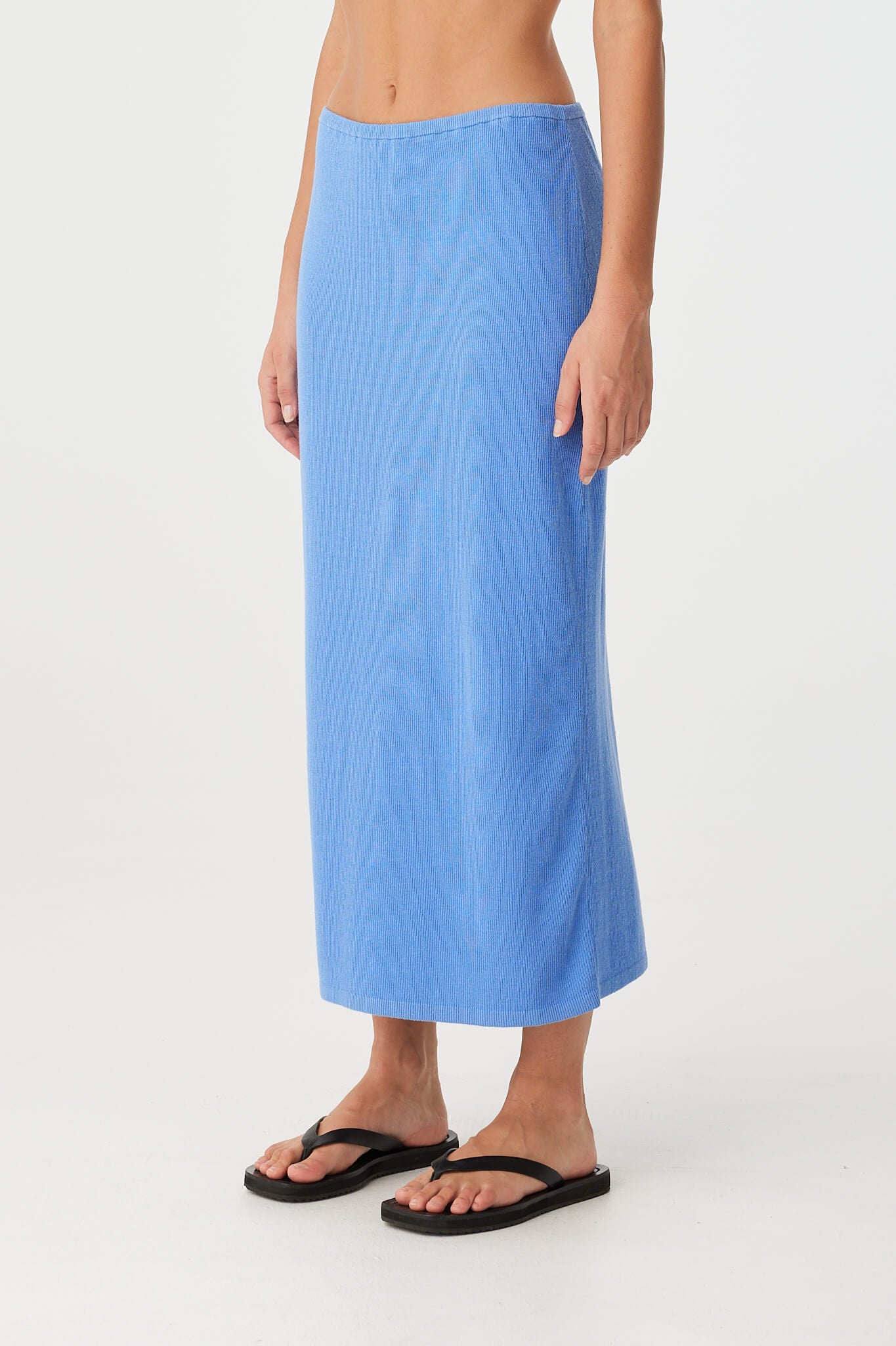 Close-up side view of blue ribbed knit skirt showing stretch texture and clean elasticated waist finish.