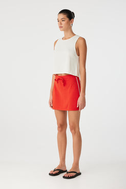 Side profile of cream knit tank with flared hem and clean finish, ideal for casual layering.