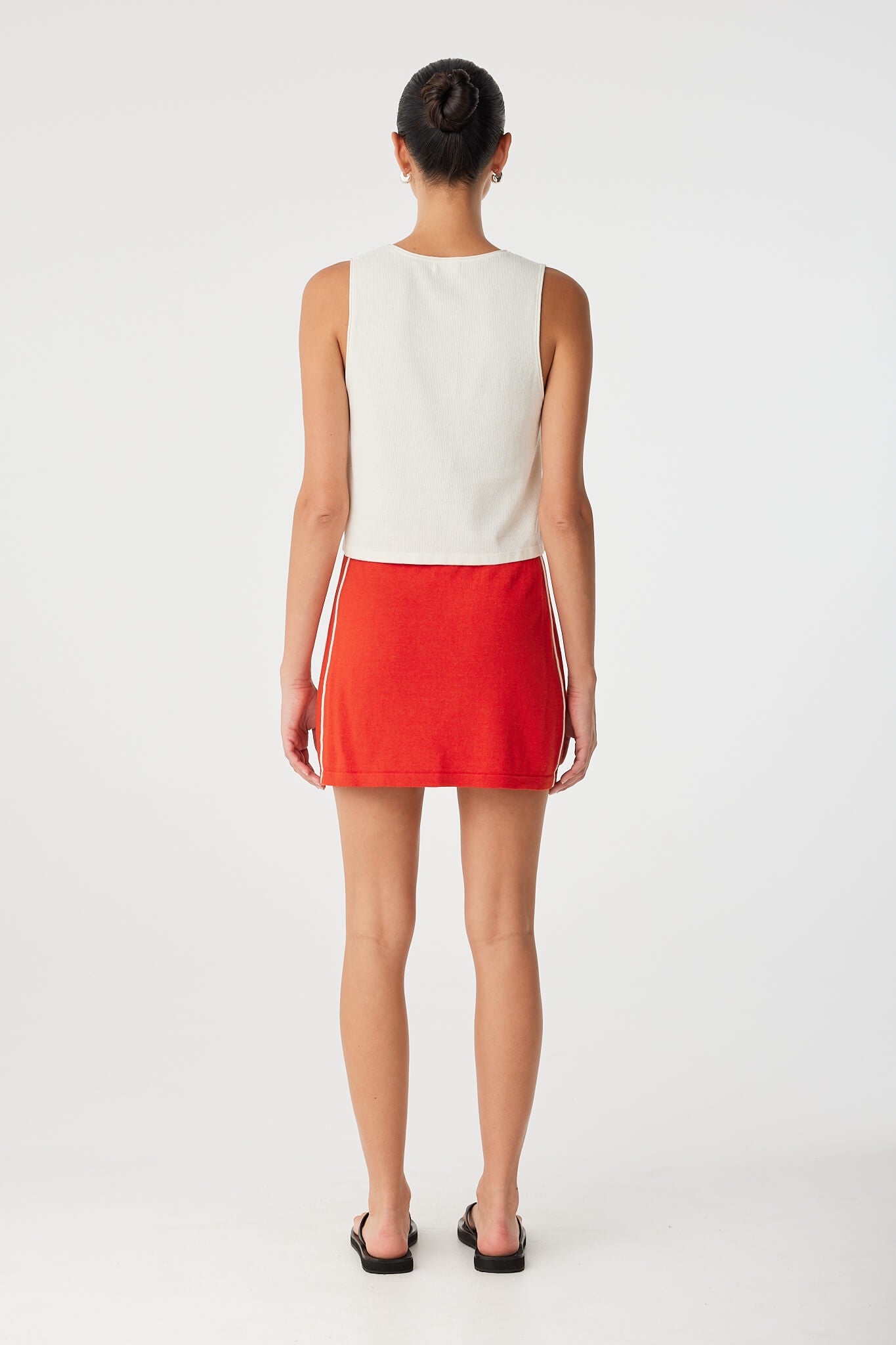 Full back view of red mini skirt with sporty finish, styled with sleeveless tank for warm-weather dressing.