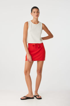 Model poses in cream tank with relaxed fit and rolled armholes, styled minimally for warm climates.