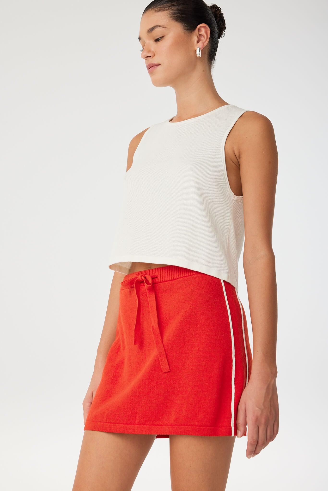 Close-up of ribbed waistband and drawcord tie on red linen–cotton mini skirt with contrast stripe—designed for ease and adjustability.