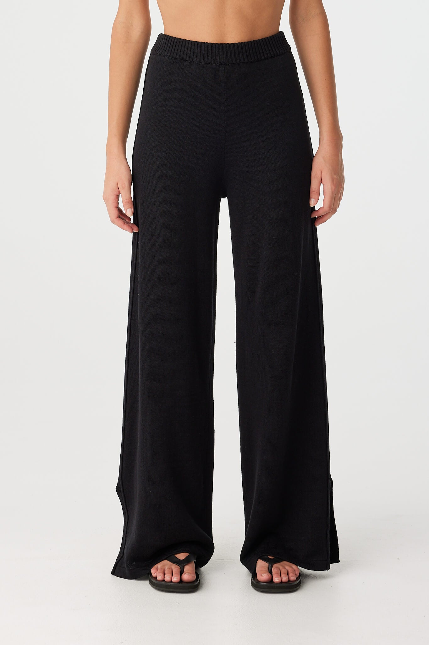 Full view of relaxed-fit wide-leg pants in black, featuring straight hem and clean side detailing for minimal summer dressing.