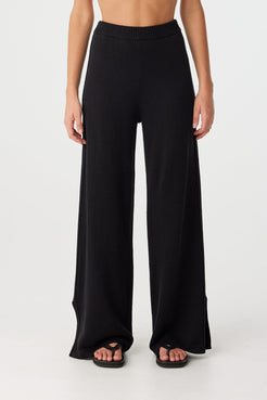 Full view of relaxed-fit wide-leg pants in black, featuring straight hem and clean side detailing for minimal summer dressing.