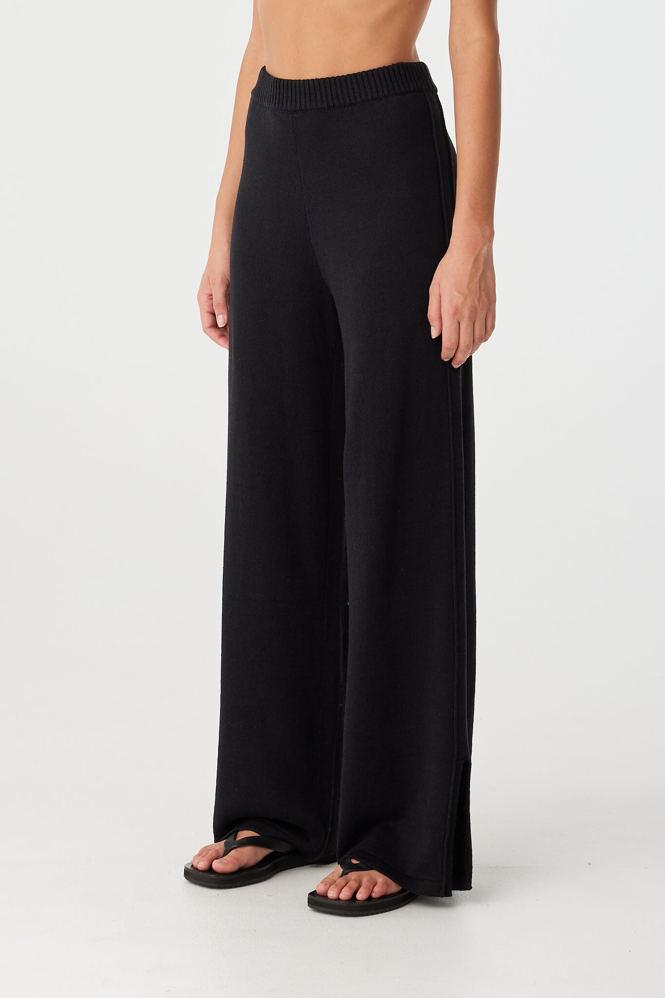 Close-up of black wide-leg pant showing ribbed waist and soft pleat at hip—crafted in lightweight linen–cotton for breathable movement.