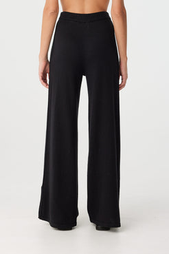 Back view of high-rise black pants with elastic waistband and wide-leg fall, designed for comfort and seasonal layering.