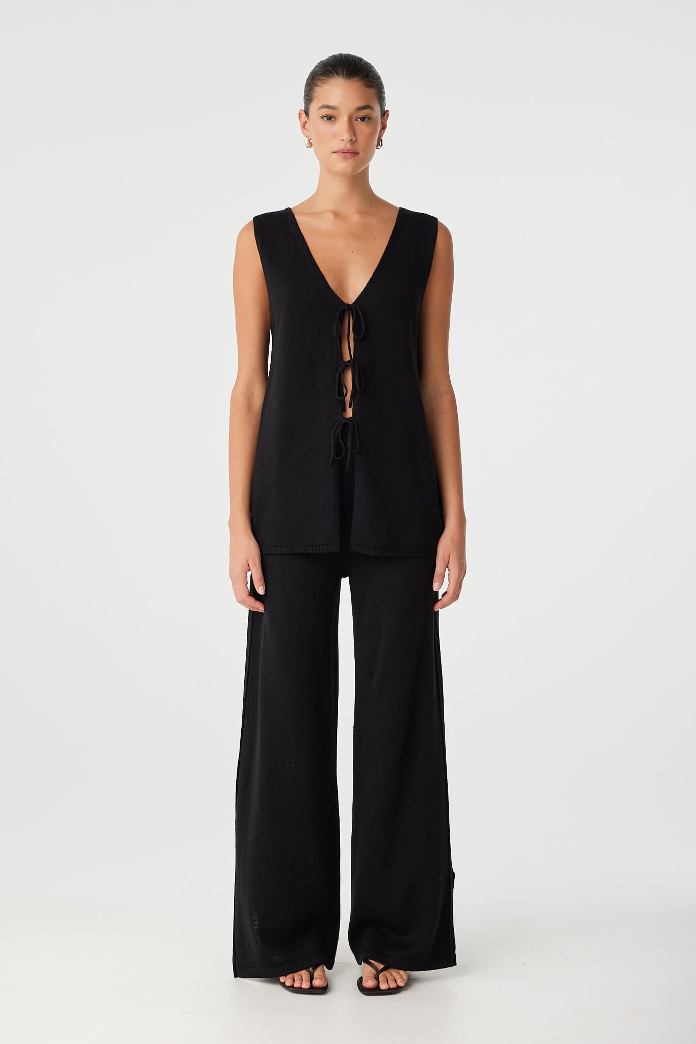 Model wears wide-leg black pants in linen–cotton blend with ribbed waistband, styled with a sleeveless top for everyday ease.
