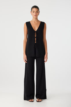 Model wears wide-leg black pants in linen–cotton blend with ribbed waistband, styled with a sleeveless top for everyday ease.