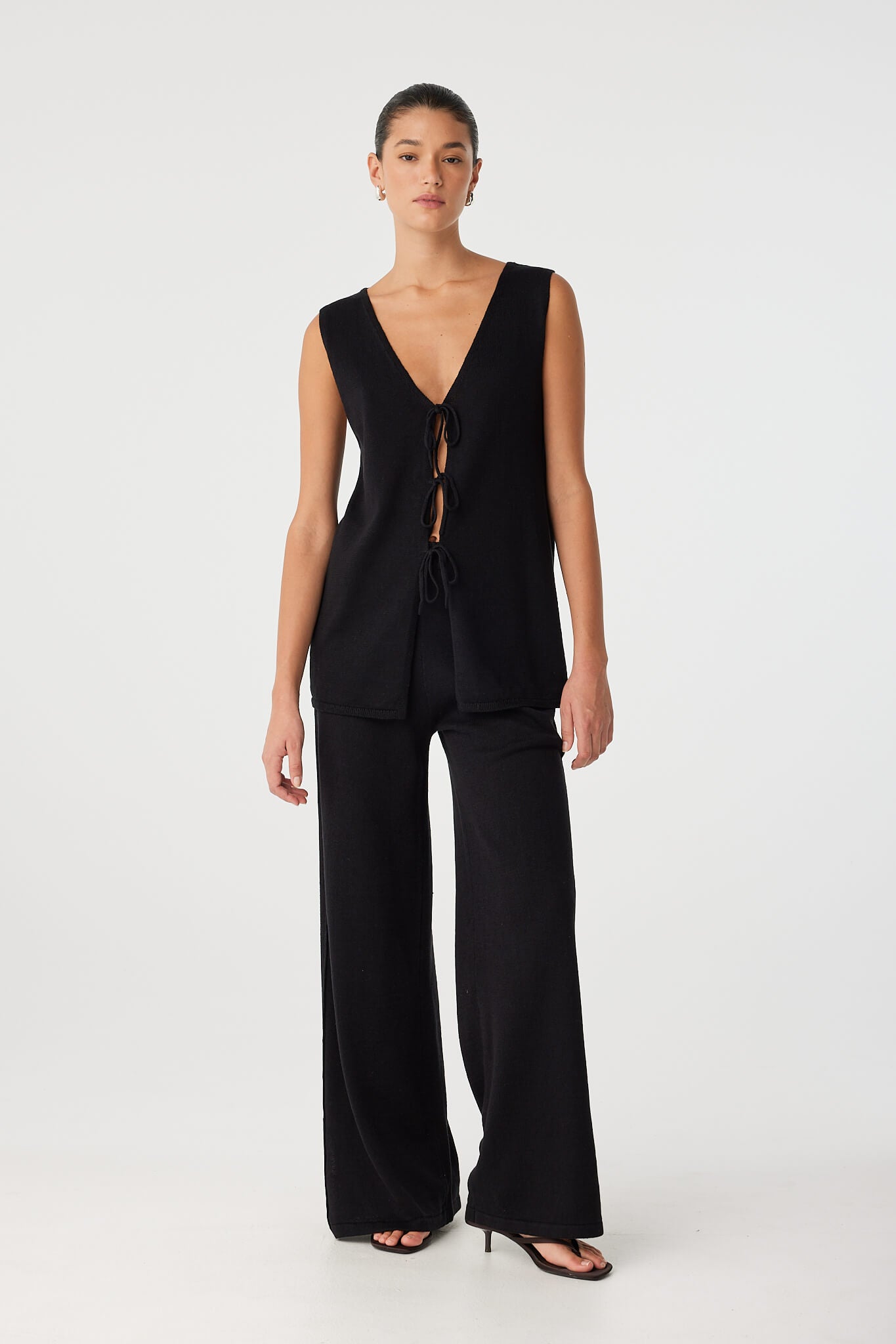Model in black reversible top with tie-front V neckline, styled with matching wide-leg pants for a minimal summer set.