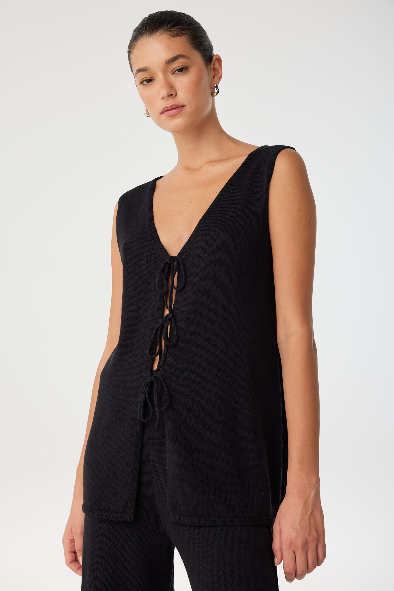 Close-up of deep V neckline and tie detail on black longline top, crafted from soft, breathable linen–cotton blend.