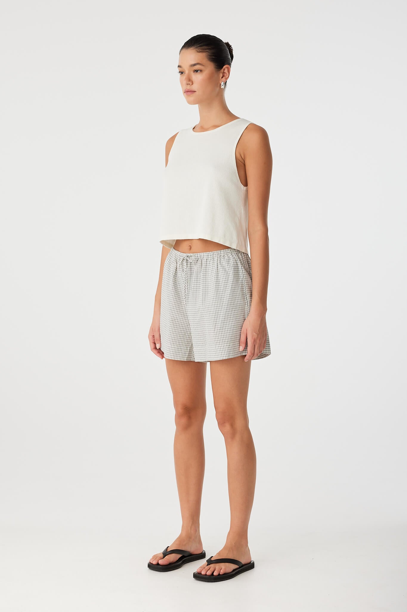 Side view of black check cotton shorts designed for airflow and casual wear, styled with flat sandals.