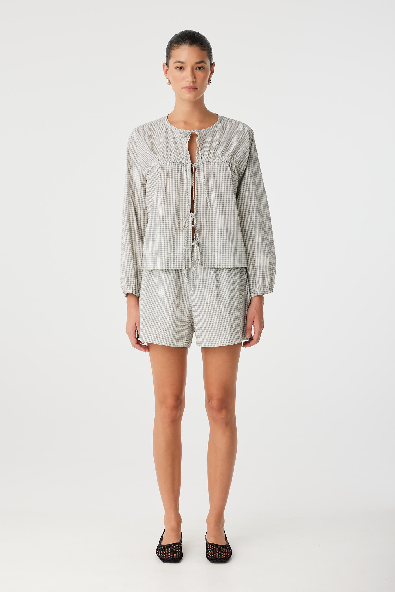 Cotton blouse in black check worn open over coordinating shorts, featuring natural volume and lightweight comfort.