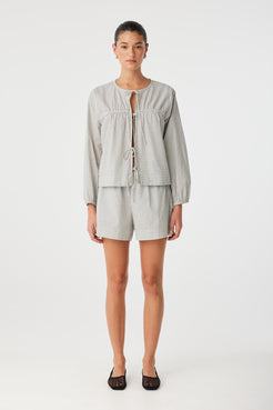 Cotton blouse in black check worn open over coordinating shorts, featuring natural volume and lightweight comfort.