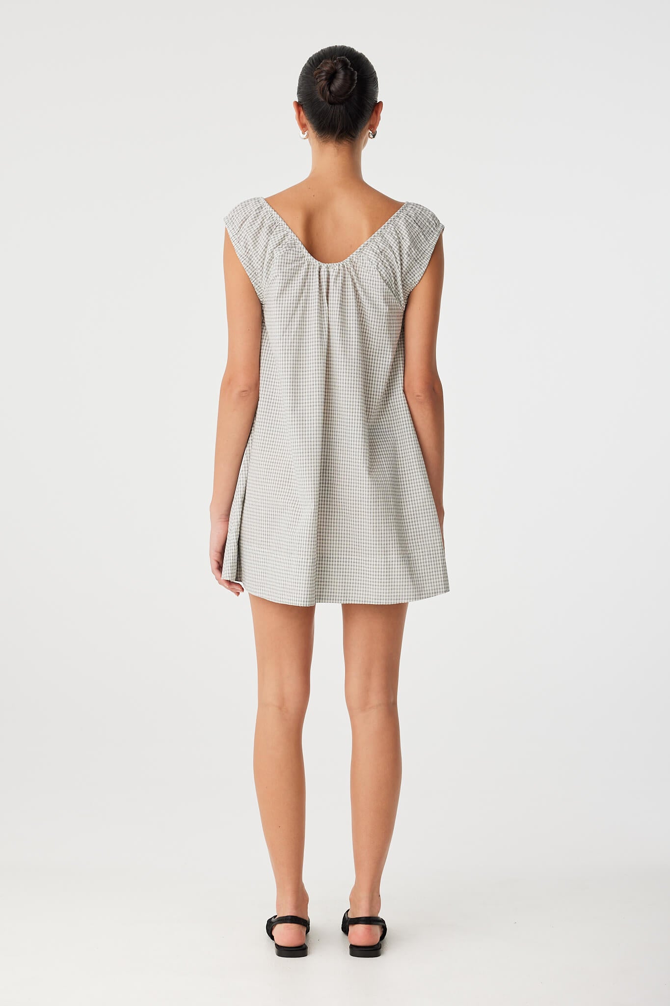 Back view of relaxed mini dress in breathable cotton, featuring scooped neckline and light movement at hem.