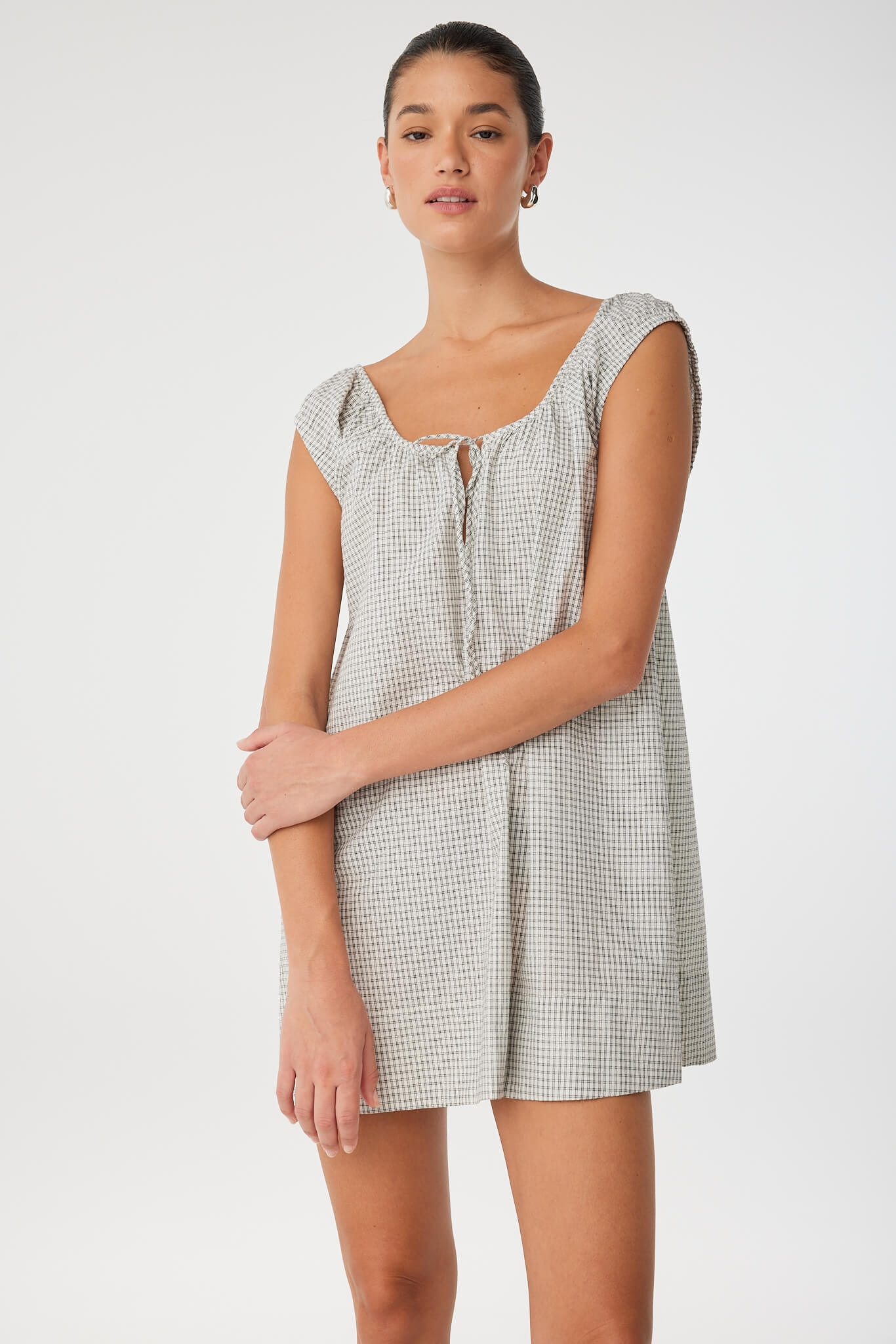 Side angle of flared mini dress in soft cotton check with adjustable neckline, offering movement and breathability for everyday wear.