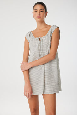 Side angle of flared mini dress in soft cotton check with adjustable neckline, offering movement and breathability for everyday wear.