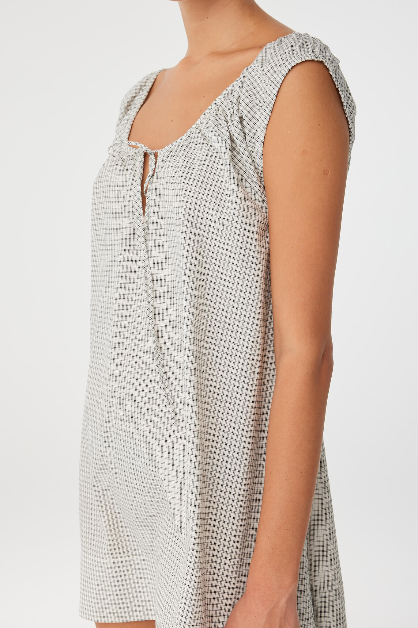 Close side profile of black check dress showing texture and flow, crafted in lightweight cotton for seasonal versatility.