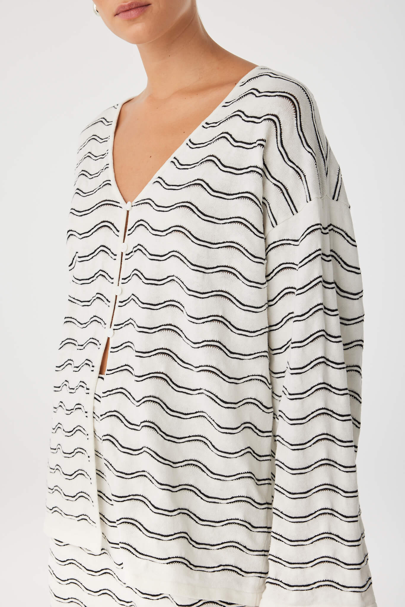 Detail of V-neckline and linen–cotton knit texture with button loop closure.