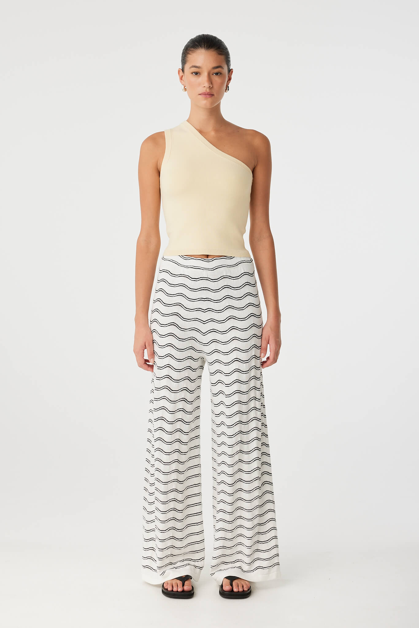 Model wears wide-leg pants in wave motif knit, styled minimally for elevated summer wear.