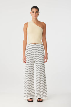 Model wears wide-leg pants in wave motif knit, styled minimally for elevated summer wear.