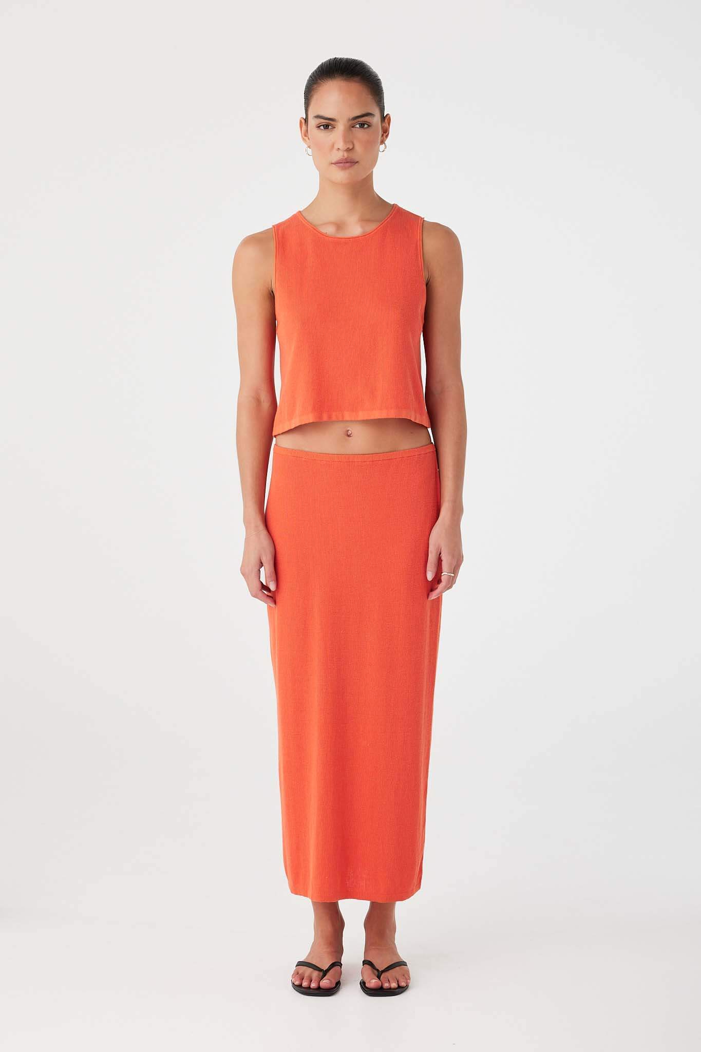 Mandarin orange knit tank with flared hemline and breathable rib texture, styled with matching skirt.